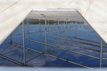 Fototapeta premium Industrial background. Reflection of a building construction from a metal frame in the phone.