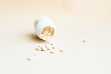 Scattered pills and open container on light background. Vitamins and remedy.