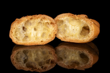 Group of two halves of baked golden profiterole one sliced isolated on black glass