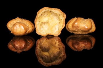 Group of two whole one half of baked golden profiterole isolated on black glass
