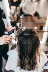 Fototapeta premium Beautiful brunette woman with long hair at the beauty salon getting a hair blowing. Hair salon styling concept.
