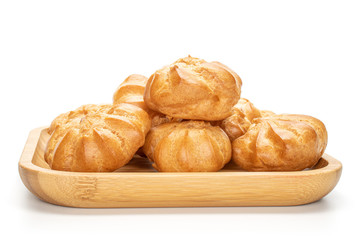 Lot of whole baked golden profiterole on wooden square plate isolated on white background