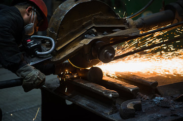 Worker grinding metal, metal grinding machine with sparks, metal sawing.