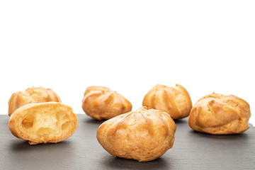 Group of five whole one half of baked golden profiterole on grey stone isolated on white background