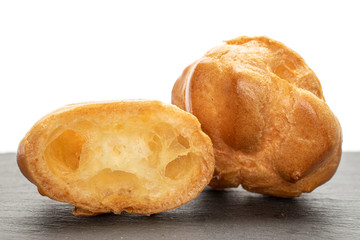 Group of one whole one half of baked golden profiterole on grey stone isolated on white background
