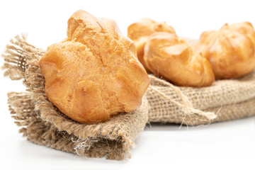 Group of four whole baked golden profiterole with jute bag isolated on white background