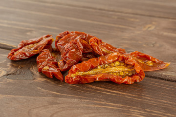 Group of five slices of dry red cherry tomato heap on brown wood