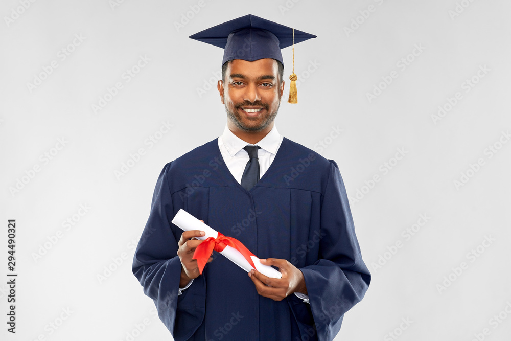 Poster education, graduation and people concept - happy smiling indian male graduate student in mortar board and bachelor gown with diploma over grey background