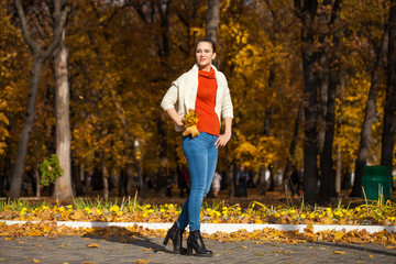 Obraz premium Young beautiful woman in blue jeans posing in autumn park