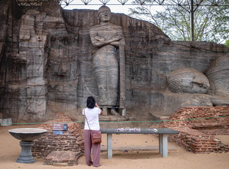 Tourist at The granite Buddha statue at The Polonnaruwa Vatadage - ancient Buddhist structure.