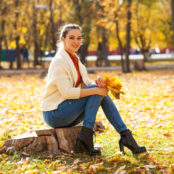 Young beautiful woman in blue jeans posing in autumn park