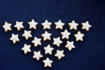 Many home-baked cinnamon stars isolated in front of dark blue Background.
