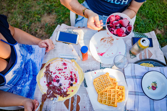 People making a picnic with sweet waffle and pancaces in the garden.