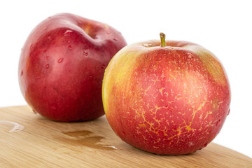 Group of two whole red apple jonagold on bamboo cutting board isolated on white background