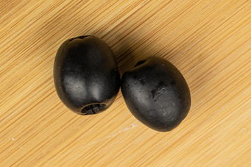 Group of two whole tasty black olive flatlay on light wood
