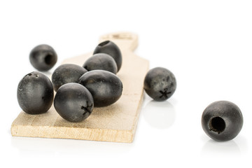 Lot of whole disordered tasty black olive on wooden board isolated on white background