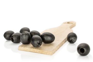 Lot of whole disordered tasty black olive on wooden board isolated on white background
