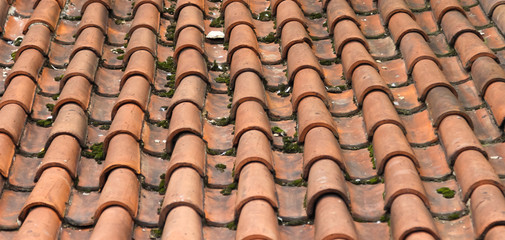 Partially damaged roof tiled with imbrices and tegulae. Photo in perspective with selective focus