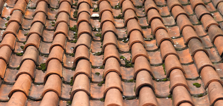 Partially damaged roof tiled with imbrices and tegulae. Photo in perspective with selective focus