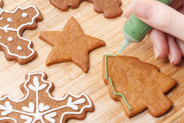 Fototapeta na wymiar Christmas gingerbread biscuits decorating process with green icing.