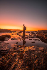 Hendaye, Aquitaine / France »; October 7, 2019: Silhouette of a young man walking on the rocks of Hendaye at a sunset