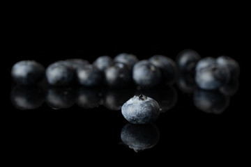 Lot of whole fresh blue blueberry front focus isolated on black glass