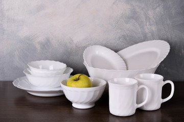  White dishware stacked on a wooden table against grey background on wooden table