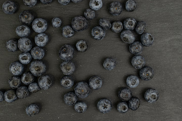 Lot of whole disordered fresh blue blueberry flatlay on grey stone