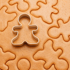 Gingerbread men background with cutter. Christmas baking texture