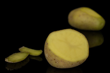 Group of one whole one half two pieces of raw brown potato isolated on black glass