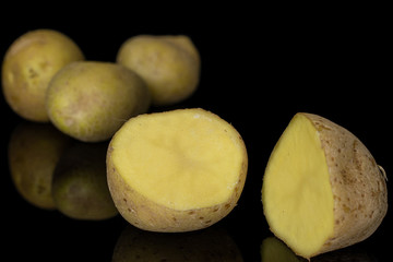 Group of three whole two halves of raw brown potato isolated on black glass