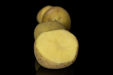 Group of three whole one half of raw brown potato isolated on black glass