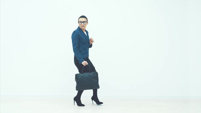 Full length portrait of a businesswoman walking with a briefcase in her hand isolated against white background