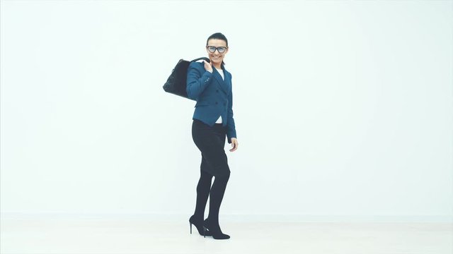 Full length portrait of a businesswoman walking with a briefcase in her hand isolated against white background