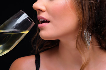 Close-up of young elegant woman drinking champagne against black background.