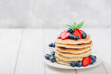 Classic american pancakes with fresh berry on white wood background. Summer homemade breakfast.