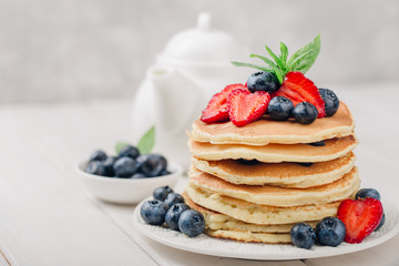 Classic american pancakes with fresh berry on white wood background. Summer homemade breakfast.