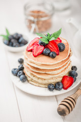 Classic american pancakes with fresh berry on white wood background. Summer homemade breakfast.