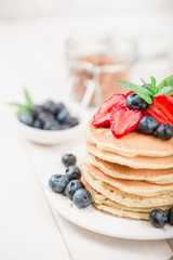 Classic american pancakes with fresh berry on white wood background. Summer homemade breakfast.