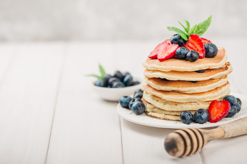 Classic american pancakes with fresh berry on white wood background. Summer homemade breakfast.