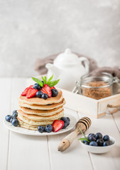 Classic american pancakes with fresh berry on white wood background. Summer homemade breakfast.