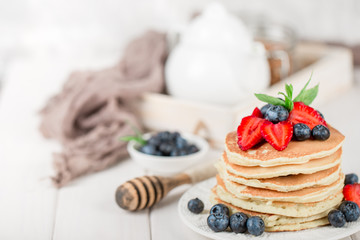 Classic american pancakes with fresh berry on white wood background. Summer homemade breakfast.