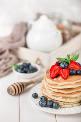 Classic american pancakes with fresh berry on white wood background. Summer homemade breakfast.