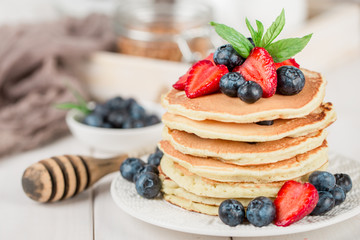 Classic american pancakes with fresh berry on white wood background. Summer homemade breakfast.