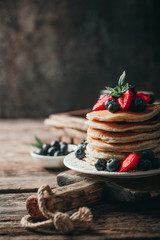 American pancakes with fresh berry on wood background. Summer homemade breakfast.