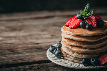 American pancakes with fresh berry on wood background. Summer homemade breakfast.