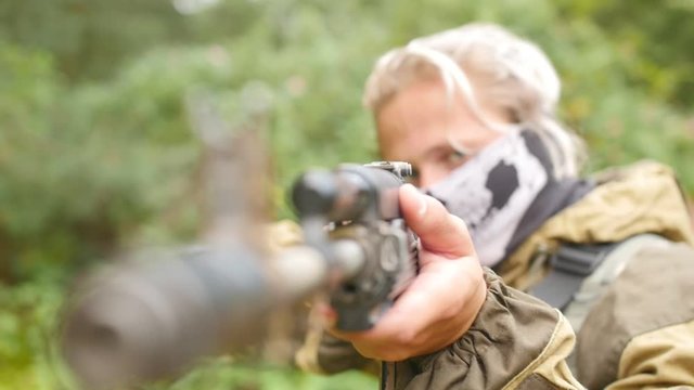 Laser tag game. The soldier looks at the sight. A man in uniform takes aim. A man plays airsoft. Close up shot.