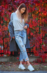 Dreamy beautiful girl with long colorful hair on autumn background of red grape hedge. Inspired...