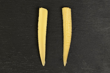 Group of two halves of baby yellow corn flatlay on grey stone