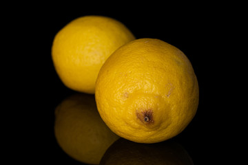 Group of two whole fresh yellow lemon isolated on black glass